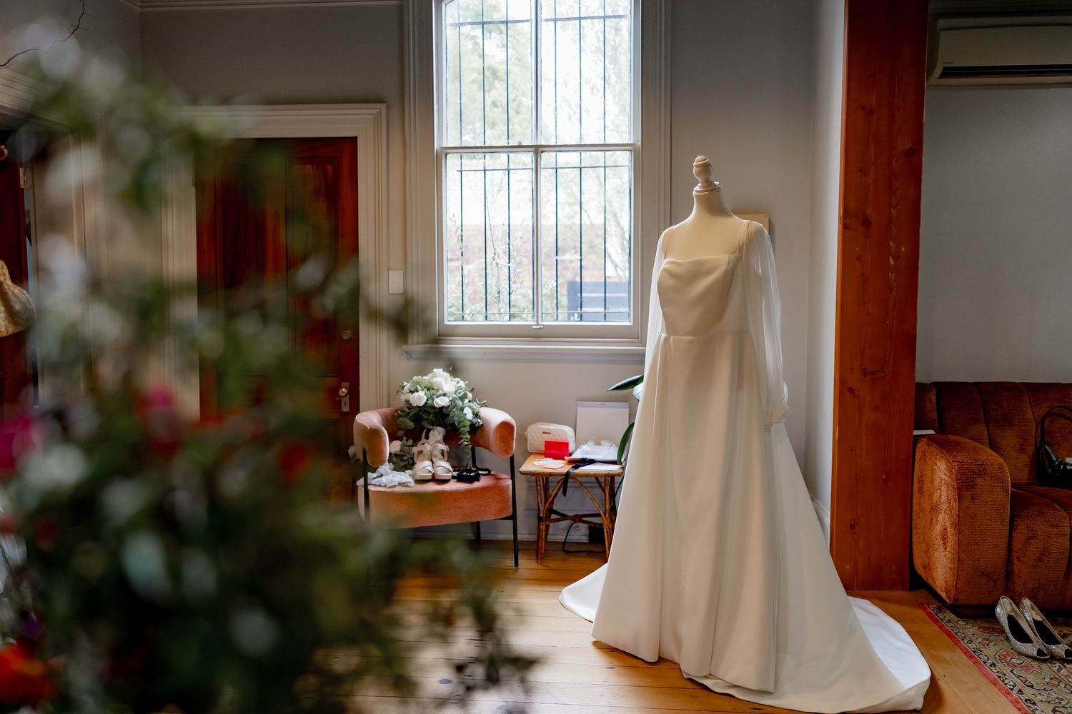 Wedding dresses on display in a sunlit room with stained glass windows and wooden floors.