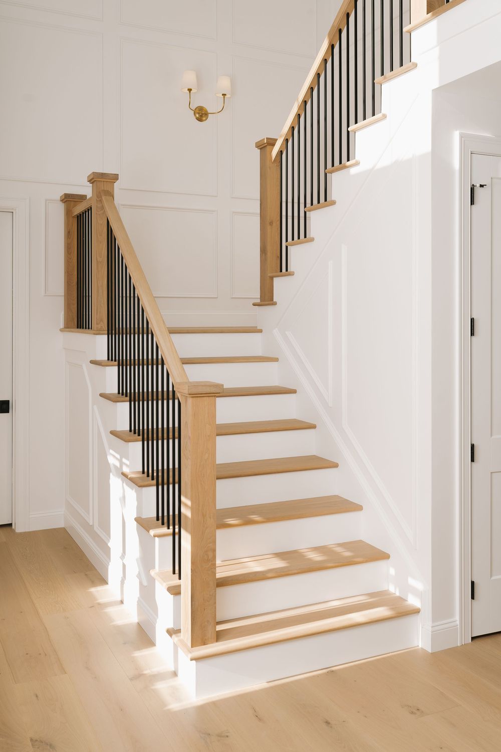 Contemporary staircase design with light wood treads and white risers against crisp white walls.