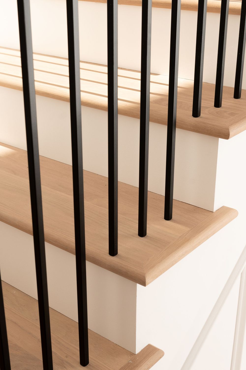 Close-up view of black metal stair balusters against wooden steps in modern home.