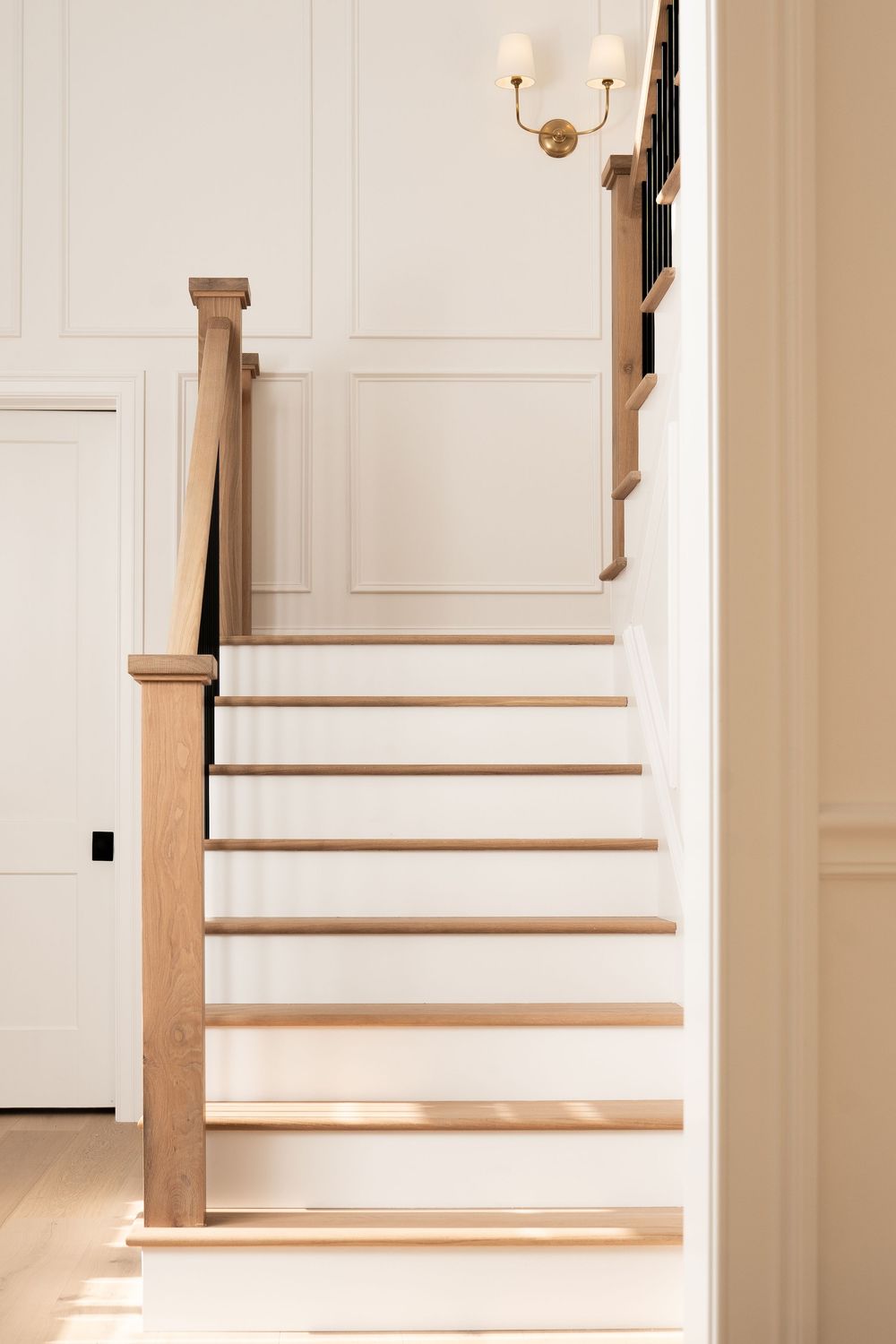 Sunlit staircase featuring white risers and natural wood treads in contemporary style.
