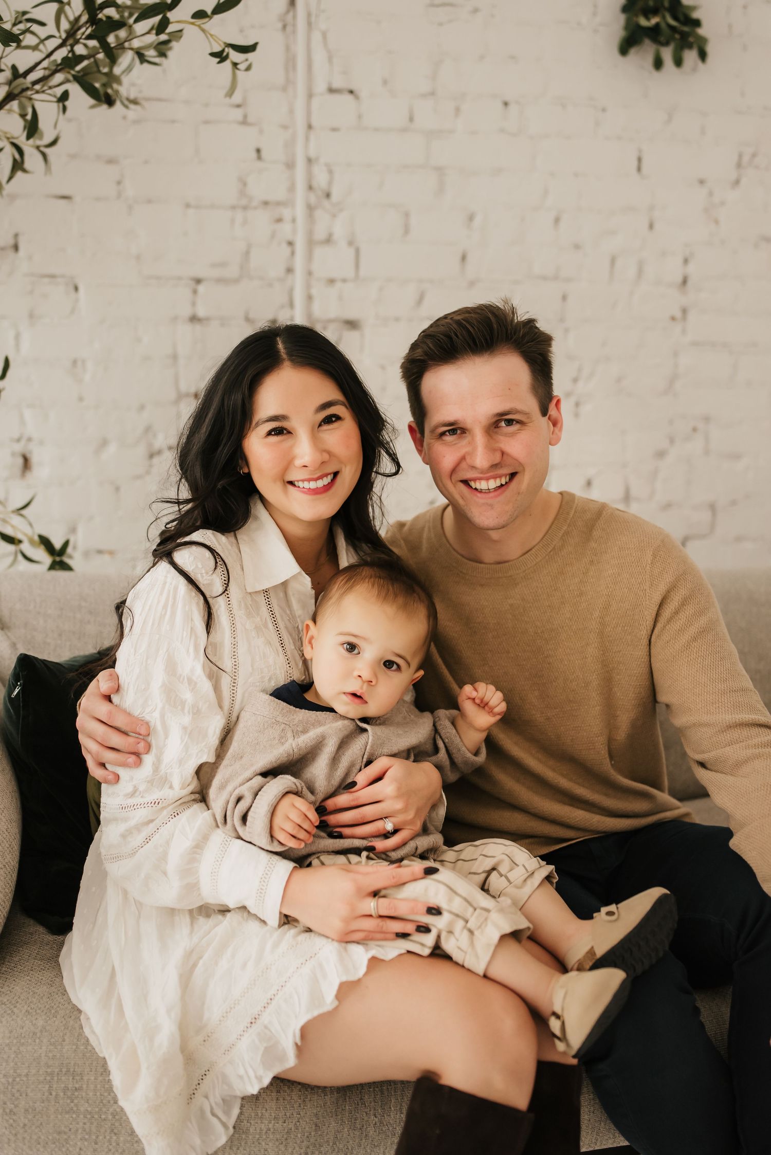 Family sitting together on a couch during a clean and modern Cincinnati studio photo session.