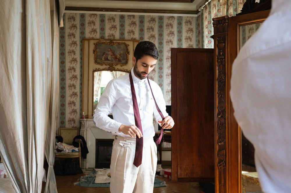 Photographe de mariage au château dans le Val de Loire photographiant le marié ajustant sa veste avant la cérémonie.