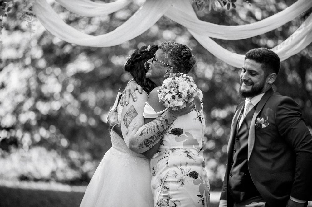 Photographe professionnelle de mariage en région Centre capturant l’émotion d’une accolade entre mariés et invités.