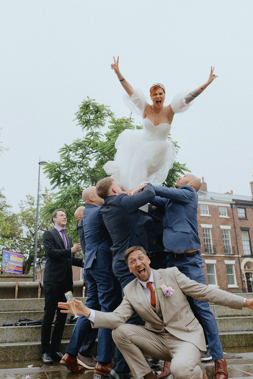 Groomsmen in suits performing playful jumping poses for wedding photos outdoors.