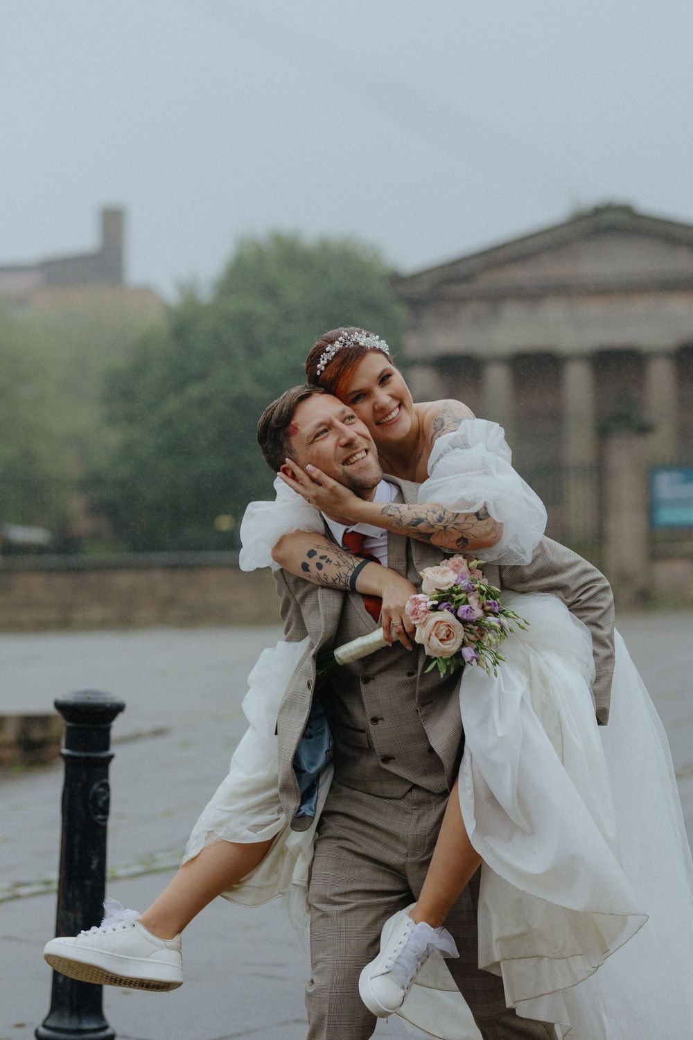 Wedding couple in grey and white sharing playful dance moves by the waterfront.