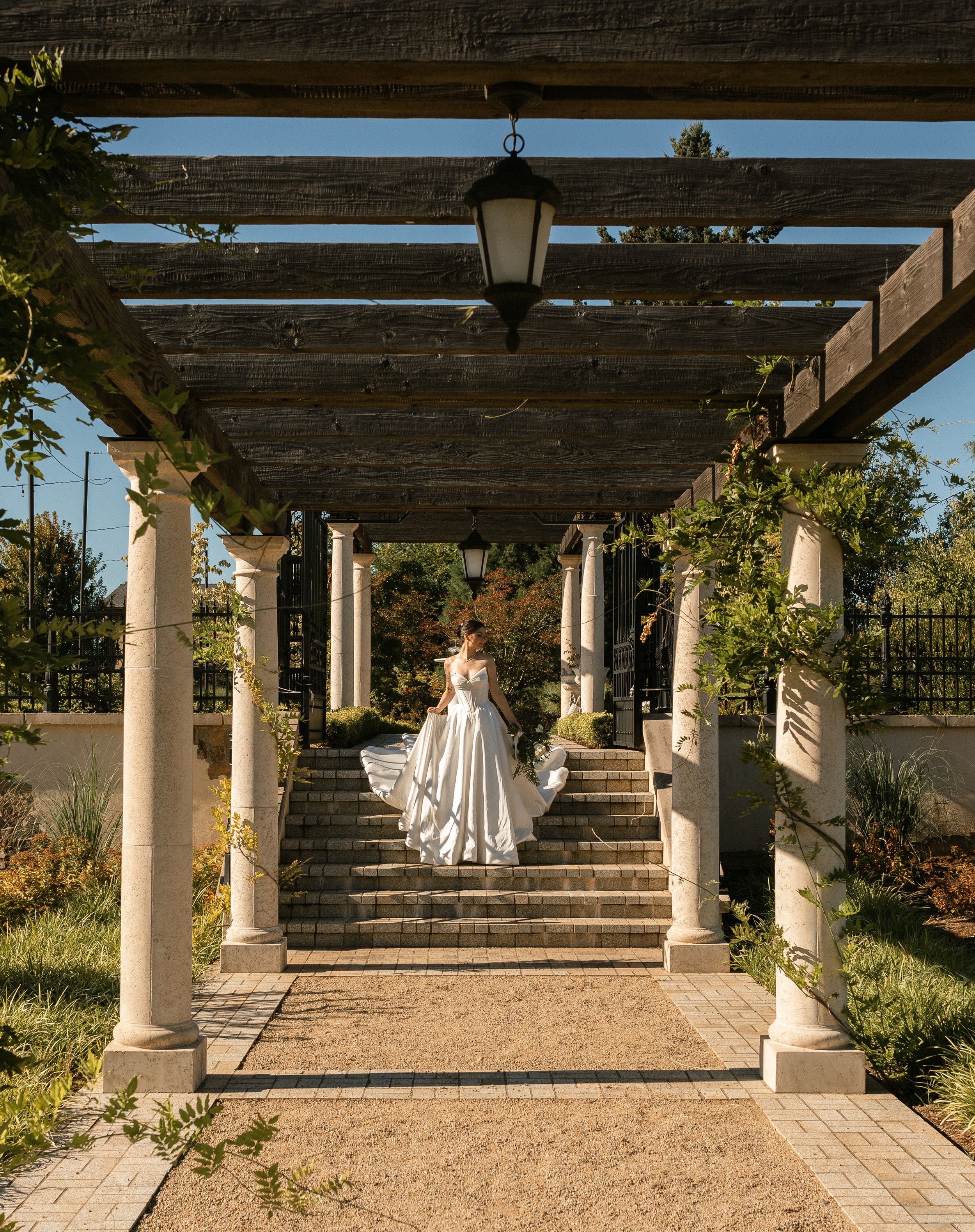 A series of elegant wedding photos captured under a rustic pergola with stone columns and garden landscaping at sunset.