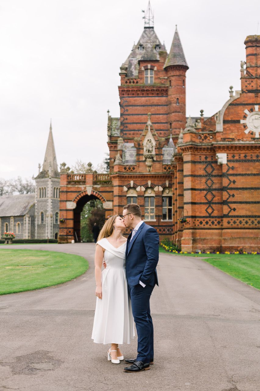 A couple shares romantic moments in front of The Elvetham which is a Victorian Gothic style brick building with ornate architecture.