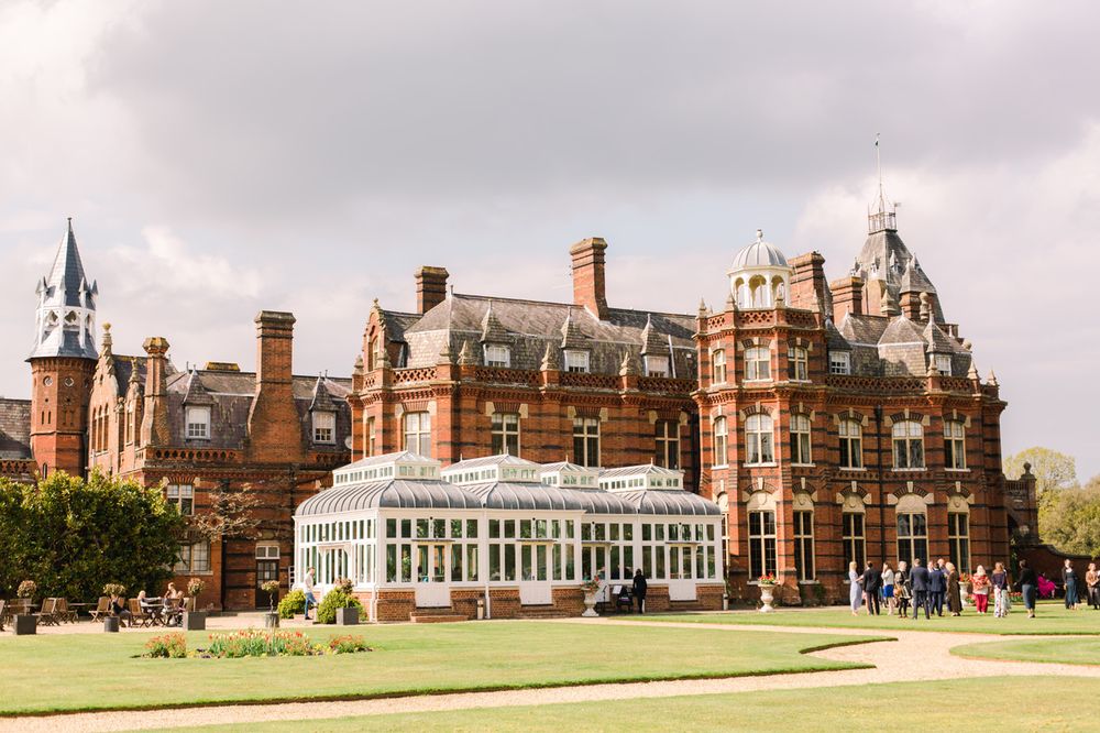 A panoramic view of historic red brick The Elvetham buildings with ornate Victorian architecture and manicured lawns.
