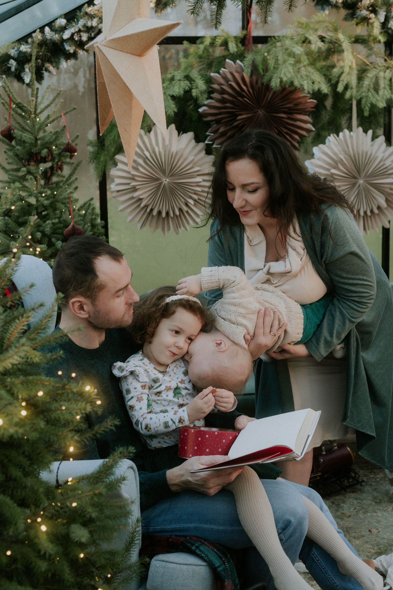 A cozy holiday scene with a decorated Christmas tree and paper fan decorations as a group reads together.