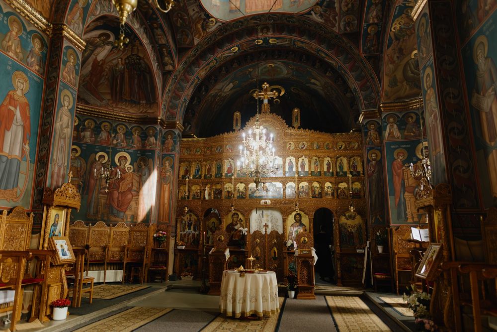 Interior panorama of an ornate Orthodox church with golden icons, chandeliers and detailed religious artwork on the walls.