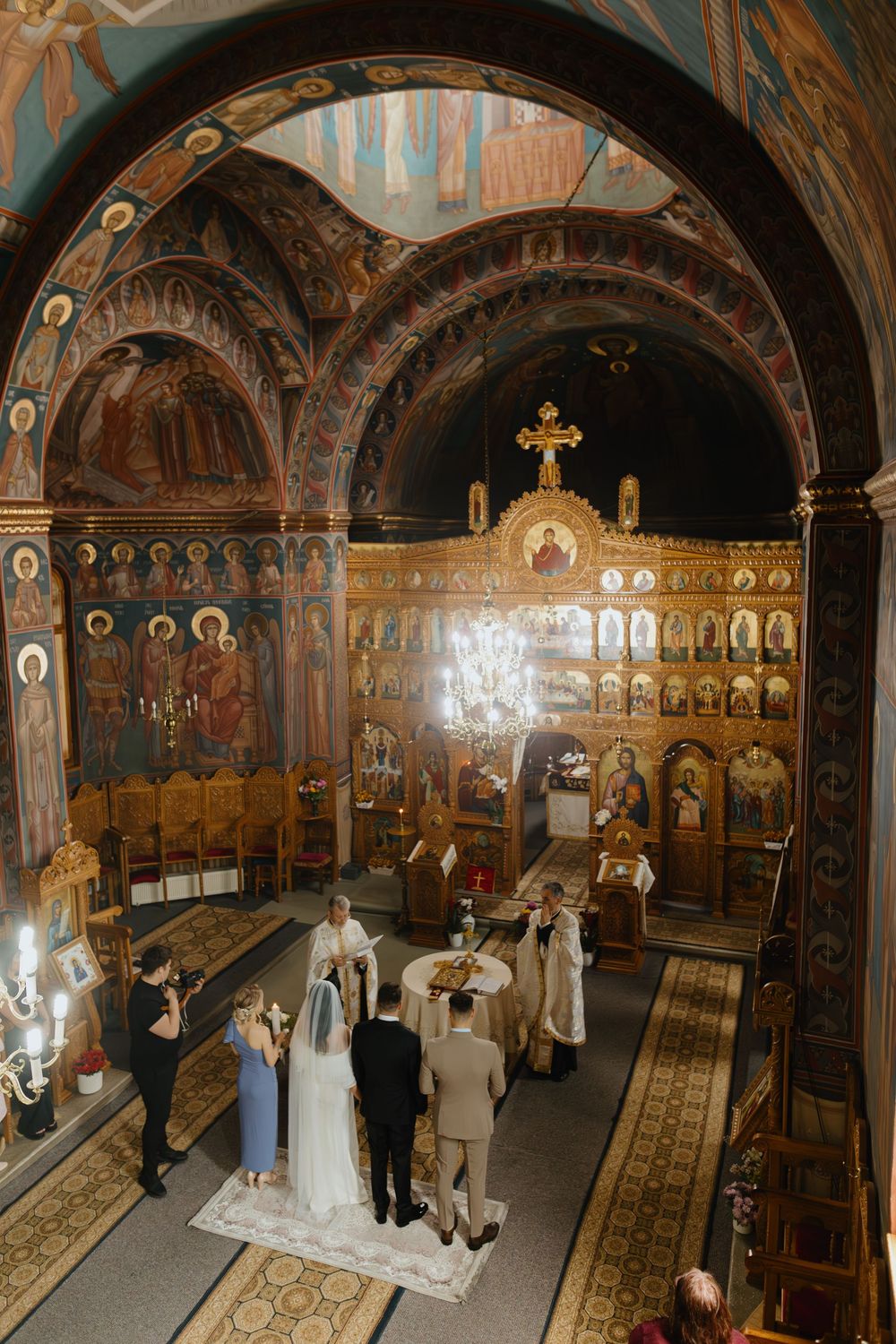 Orthodox church wedding ceremony with ornate iconography and arched ceilings in traditional Byzantine style.