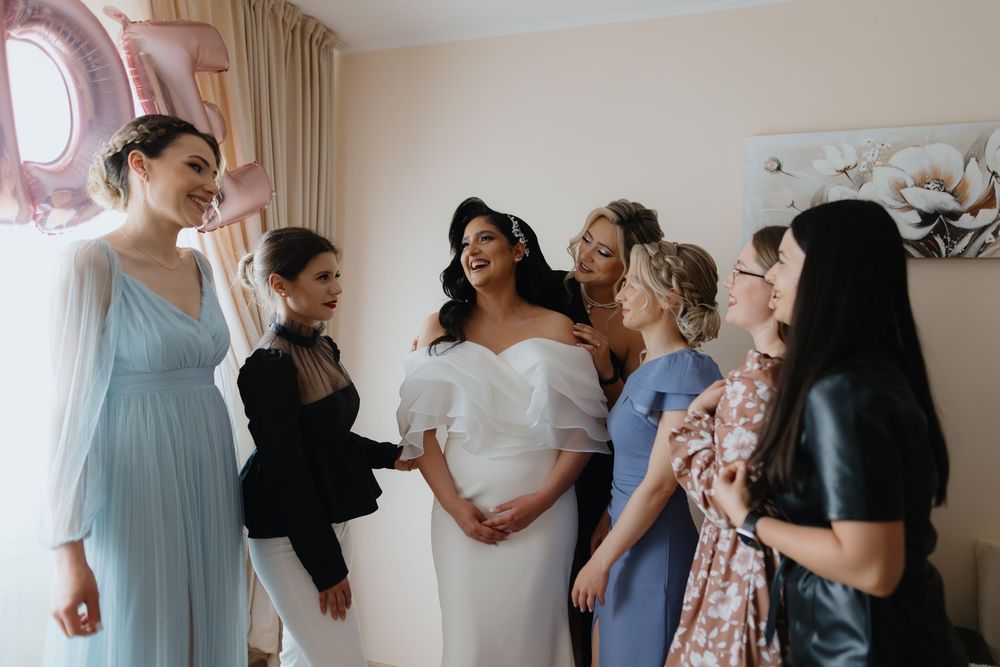 Wedding party members in pastel dresses share joyful moments together during pre-ceremony preparations.