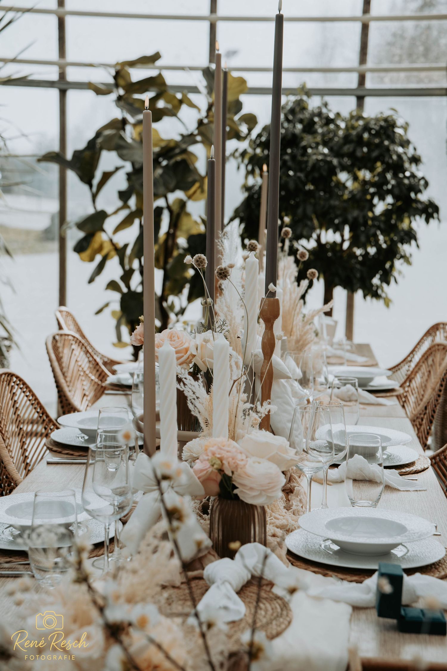 Elegantes Hochzeitsbankett mit zarten rosa Blumenarrangements und Akzenten in Roségold in einem lichtdurchfluteten Veranstaltungsort.