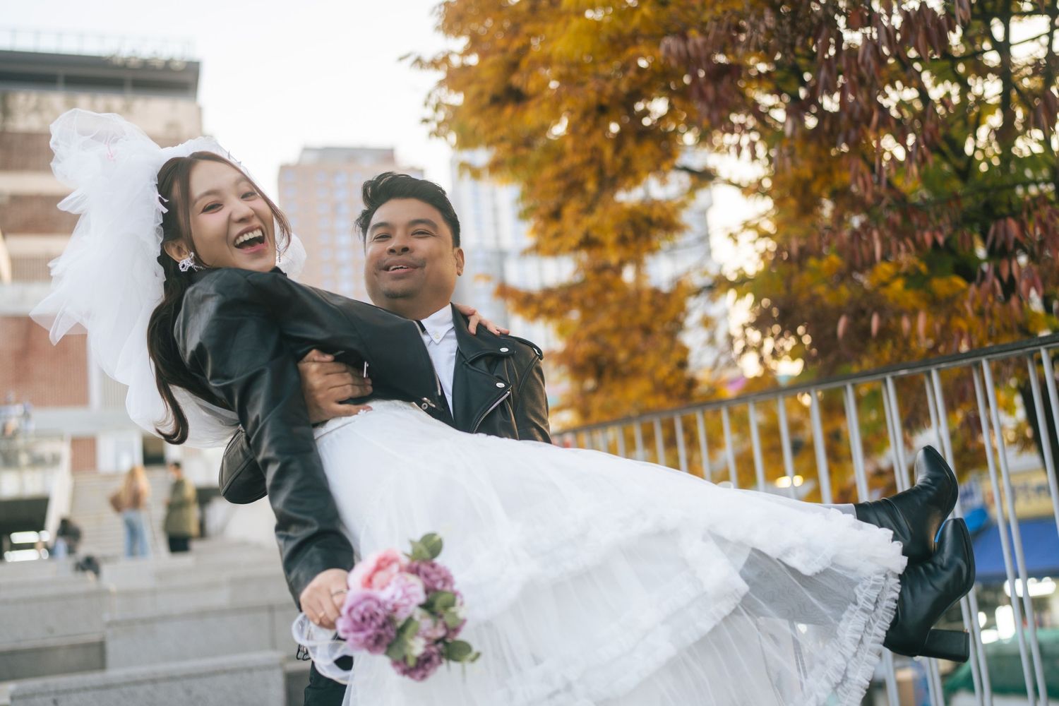 A joyful wedding couple shares a romantic moment together during their autumn photoshoot with golden leaves in the background.