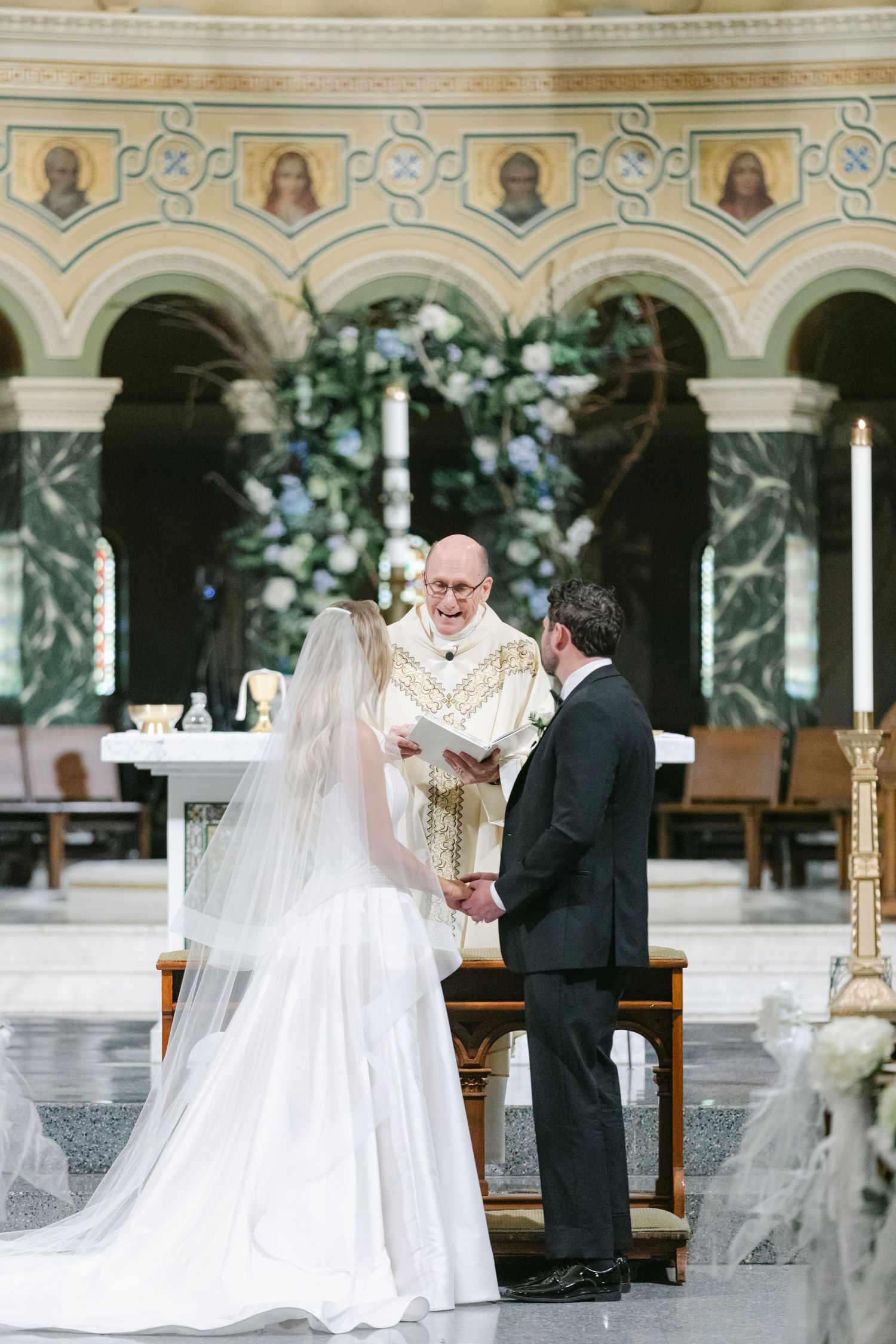 A traditional Catholic wedding ceremony taking place in an ornate church with elegant architectural details.