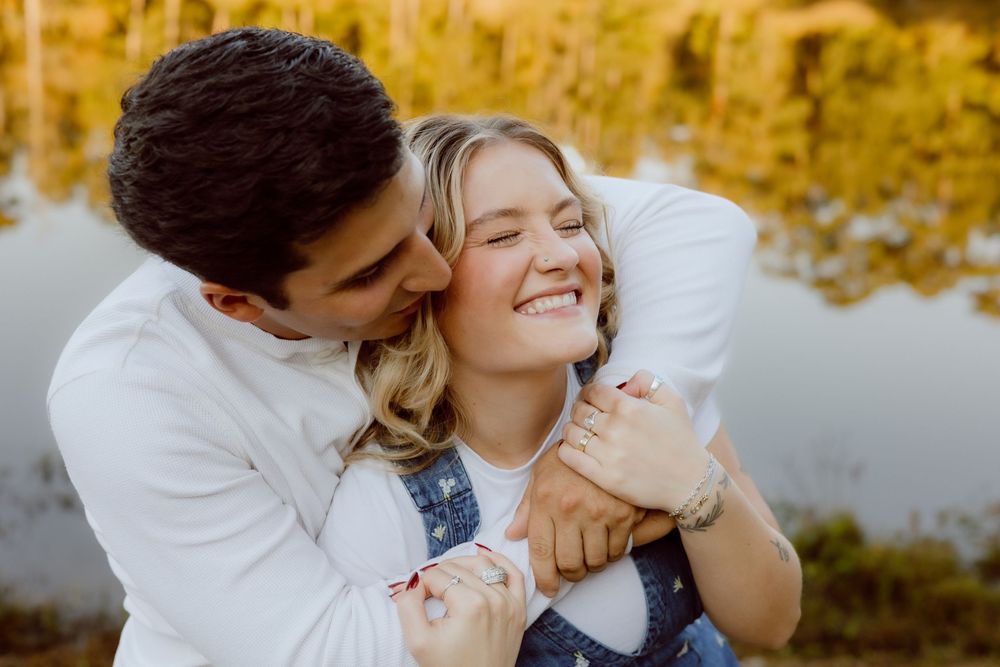 A romantic embrace captured during golden hour with a serene lake backdrop.