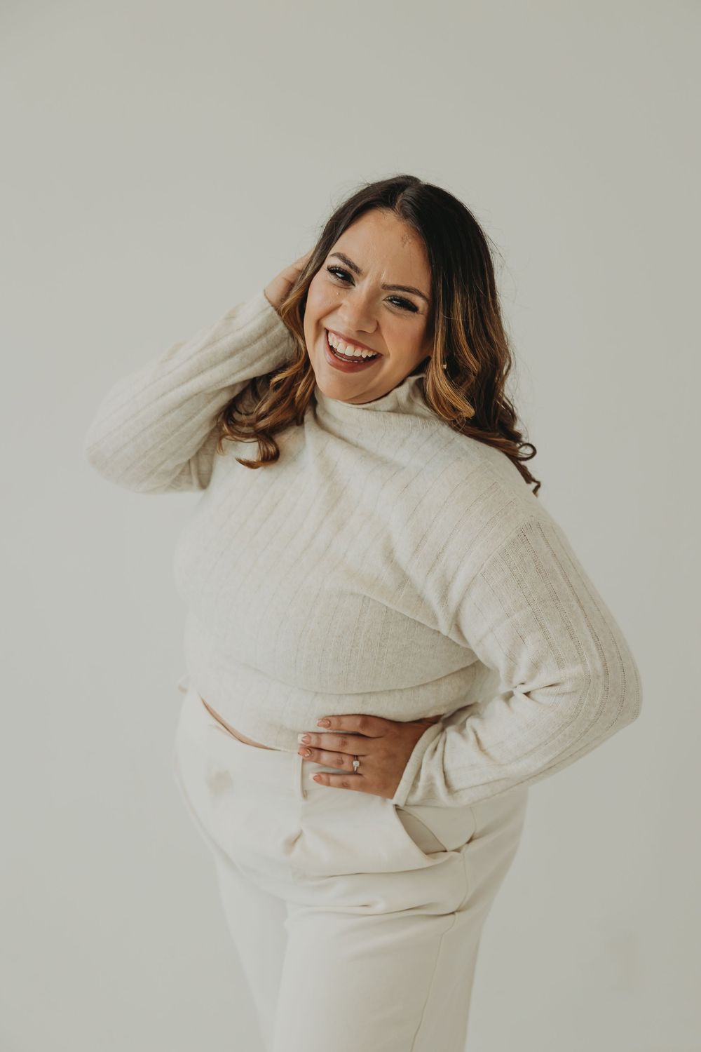 Person wearing a cozy white sweater poses playfully against a light background in a series of connected photos.