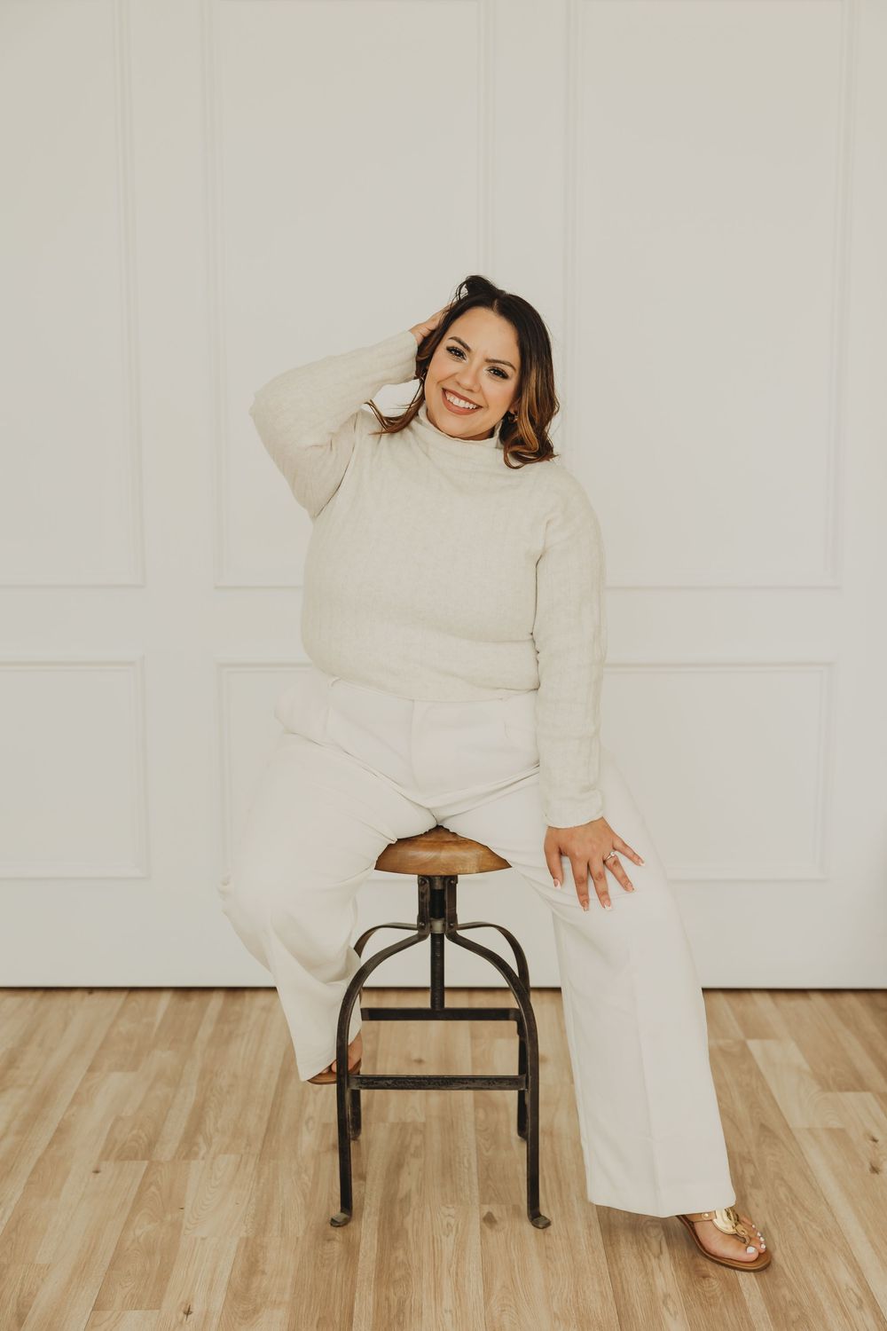 Modern minimalist portrait session with cream colored outfit against white walls and wooden flooring.