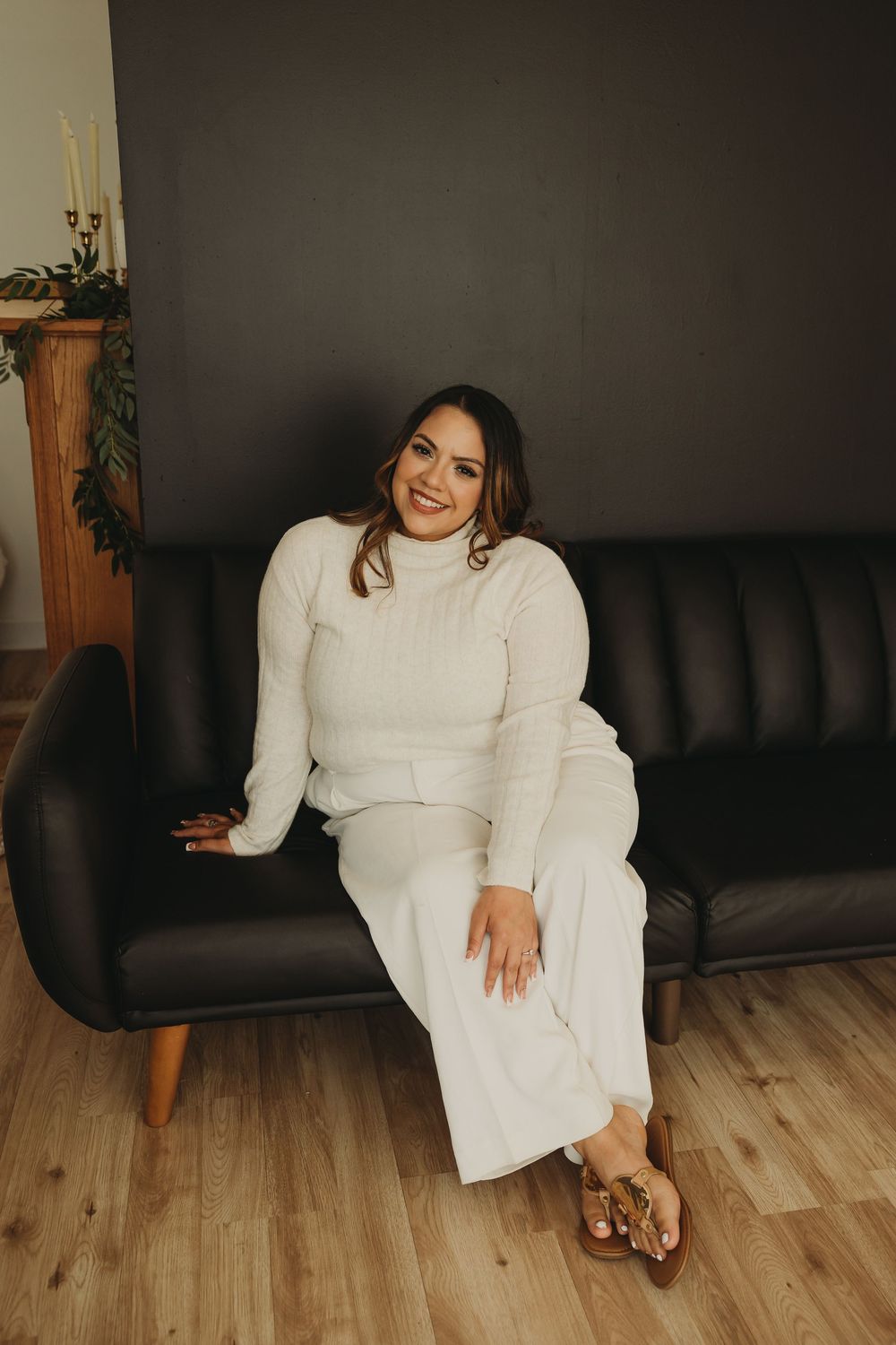 Lifestyle photoshoot featuring a white knit loungewear set against a dark couch and wooden floor backdrop.