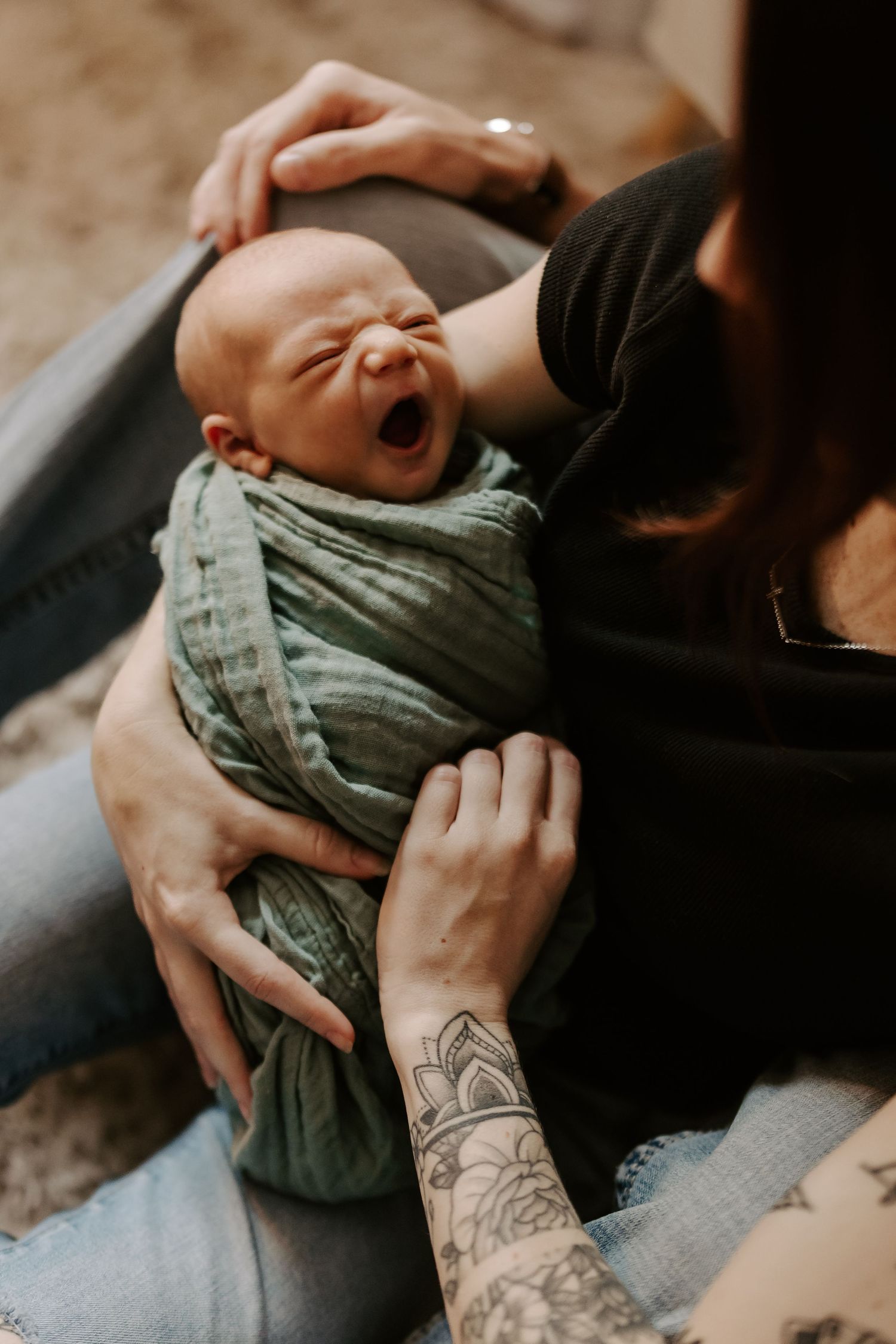 Close-up shots of hands cradling a baby wearing striped clothing, with visible tattoo details.