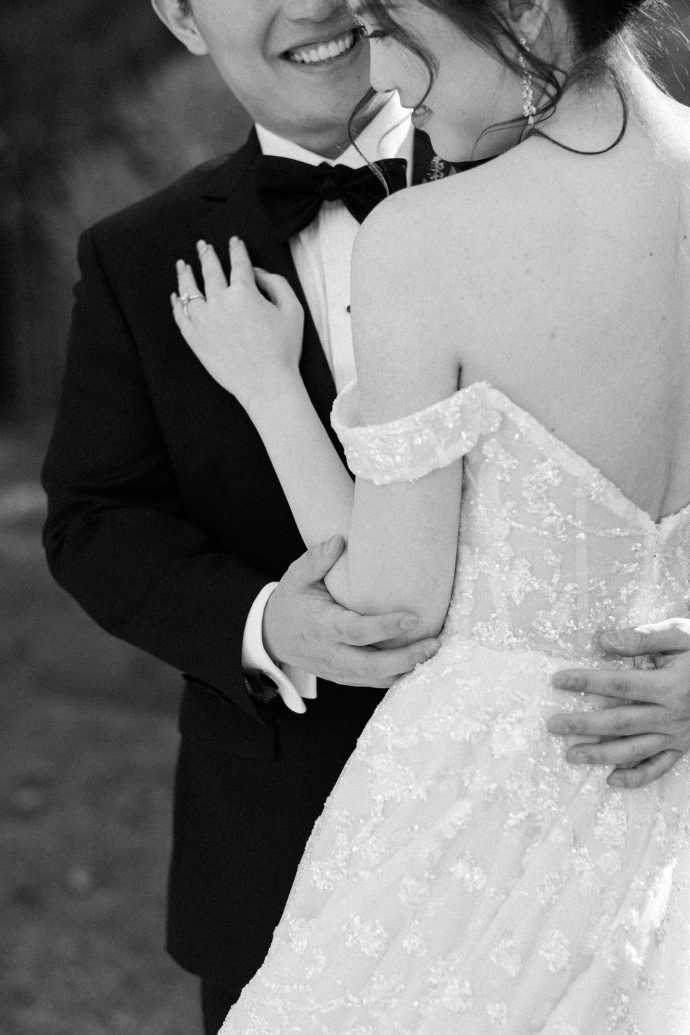 Black and white wedding photo showing close-up details of a sparkly white wedding dress and formal attire.