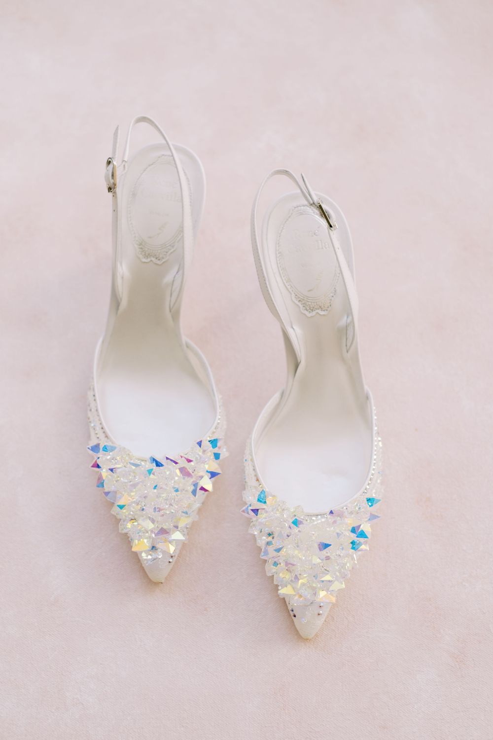 Elegant white slingback bridal shoes with iridescent crystal embellishments on the pointed toe.