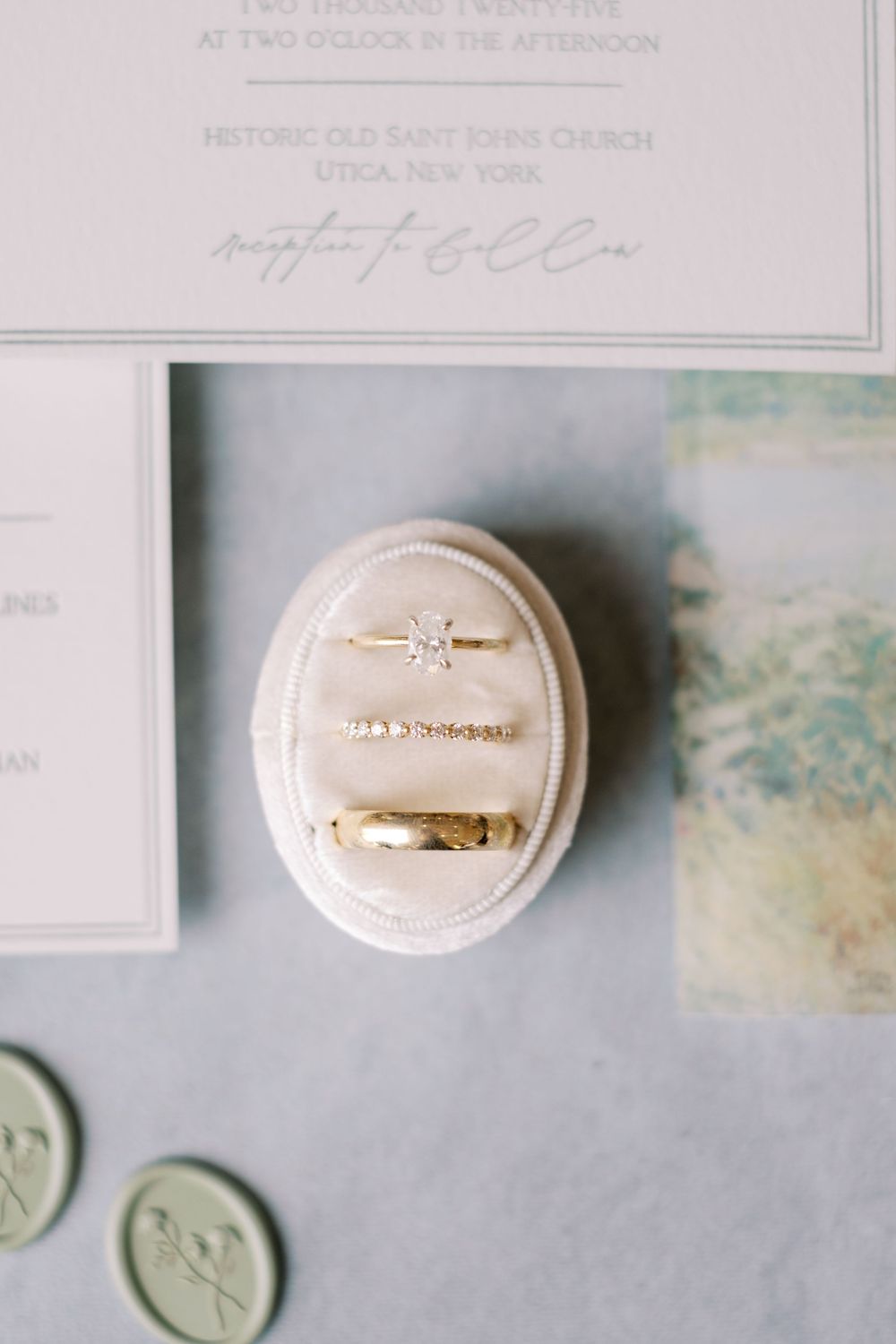 White ceramic wedding rings and wax seals arranged on a light gray textured surface.