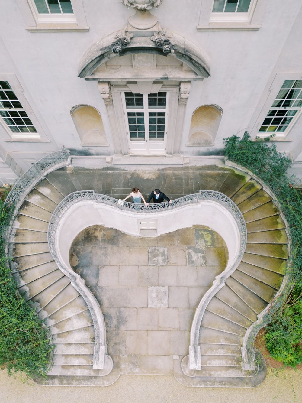Architectural detail showing four curved stone staircases with elegant railings against a white building facade.