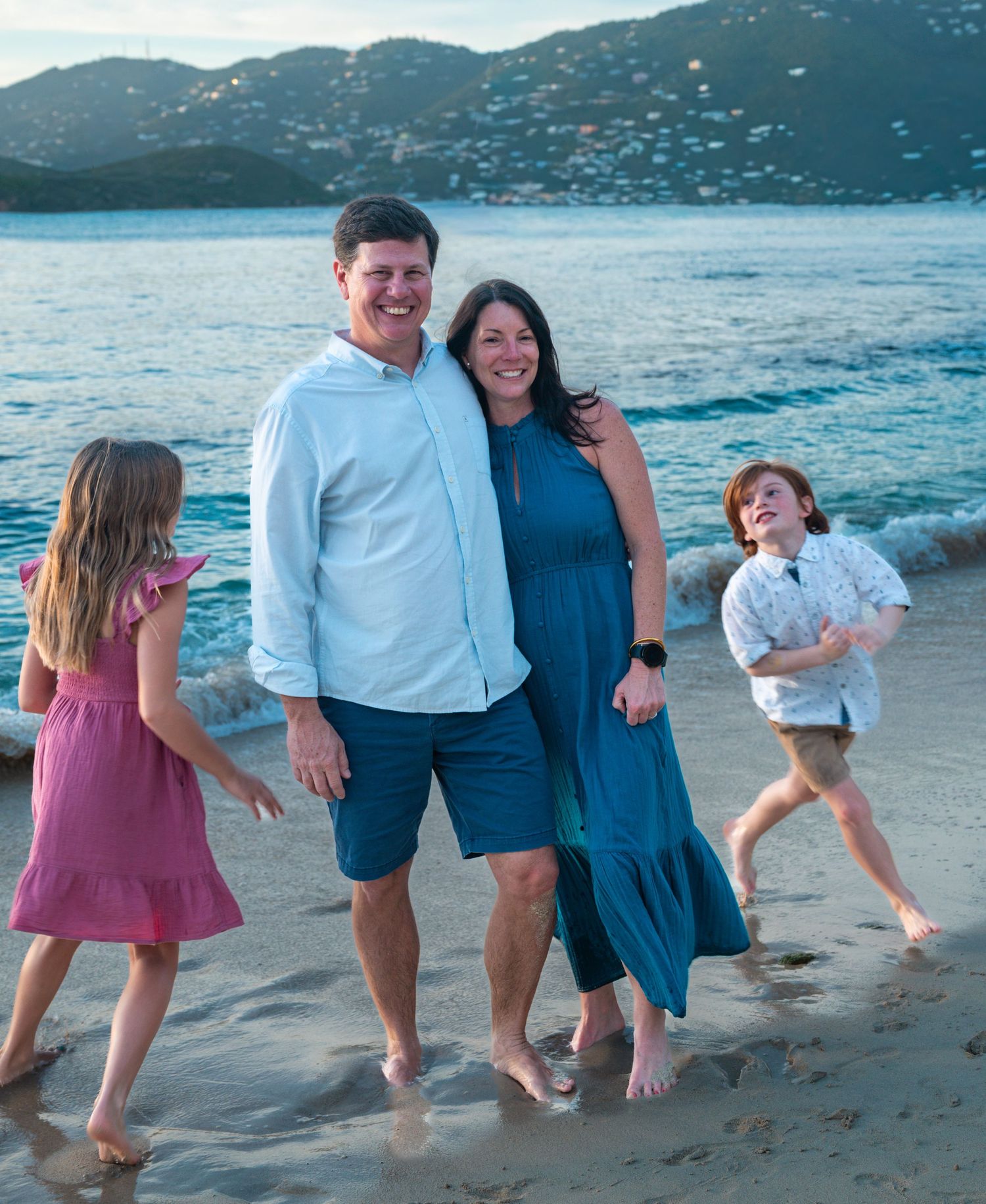 Kids run around parents on the beach.
