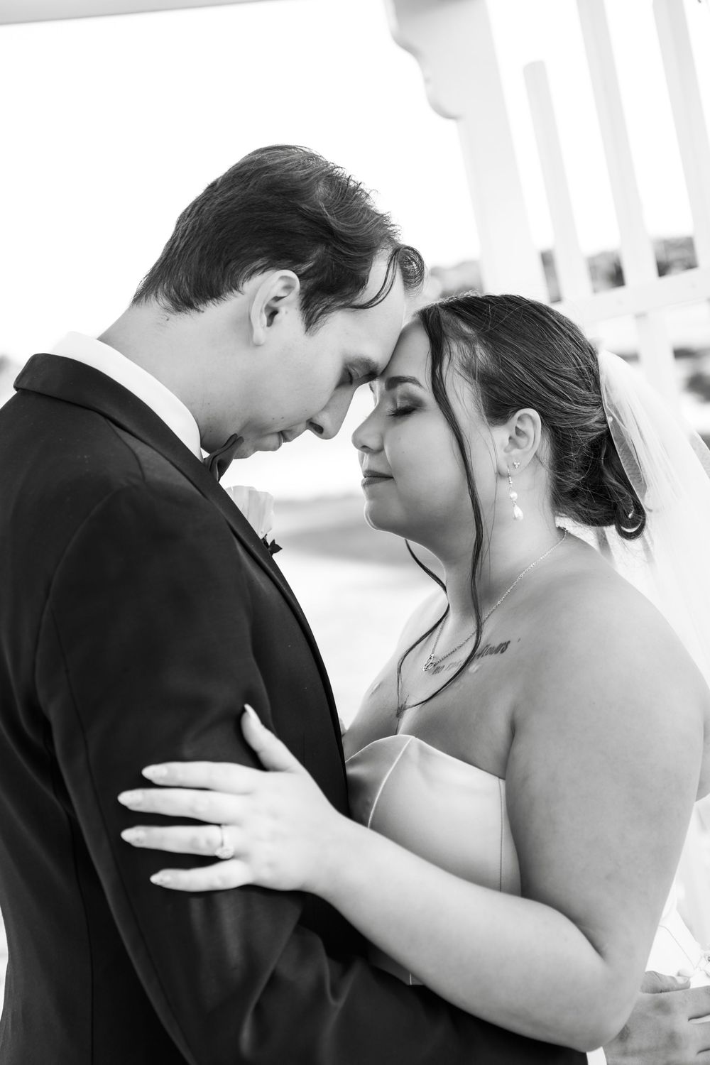 Black and white intimate portrait of bride and groom touching foreheads tenderly during their wedding day.