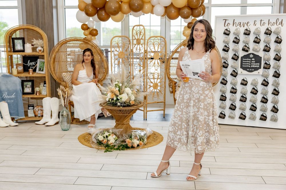 brides pose in an elegant boho-styled event space with balloon arch, rattan decor, and floral arrangements.