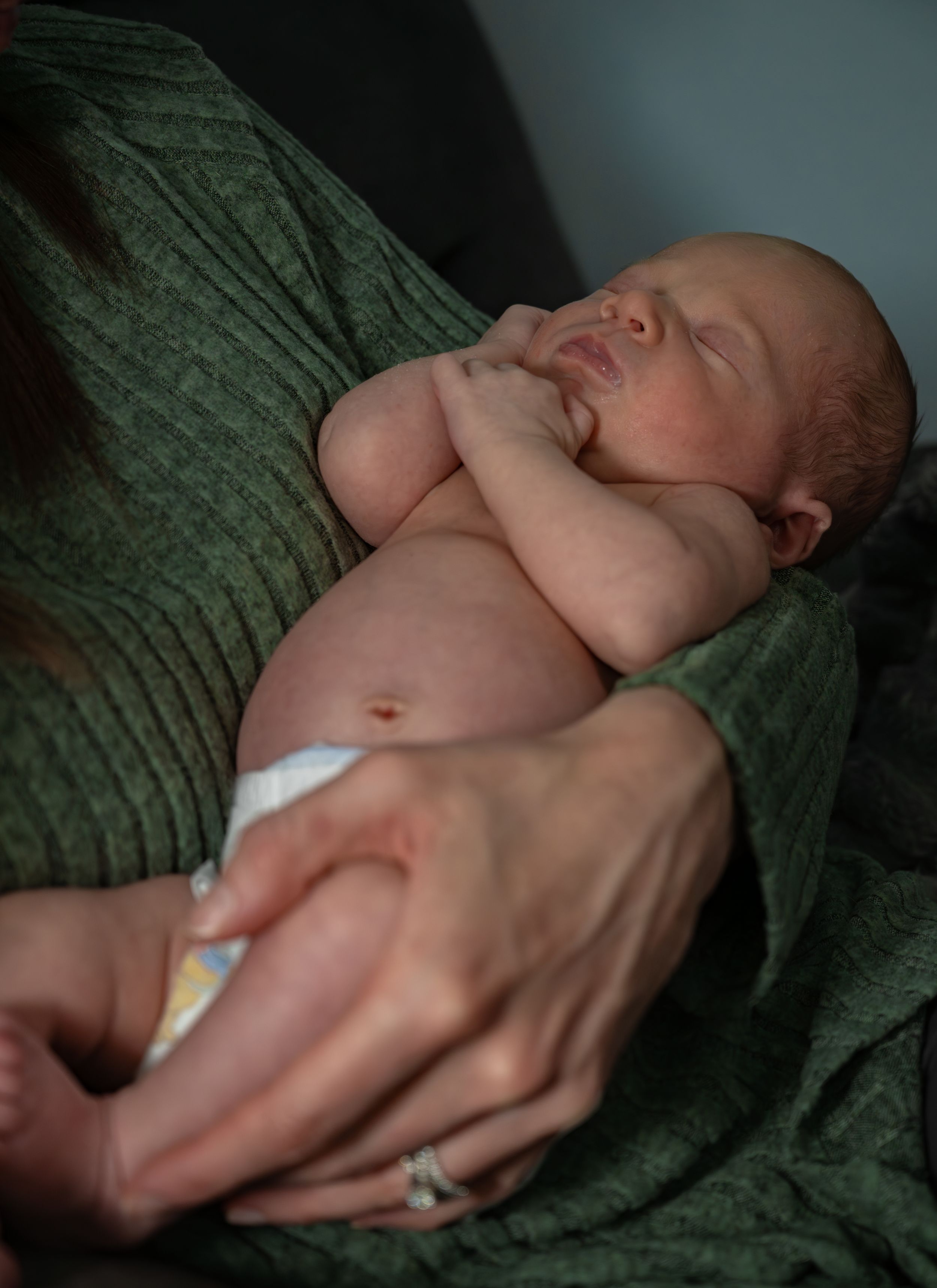 A baby boy held by his mom.