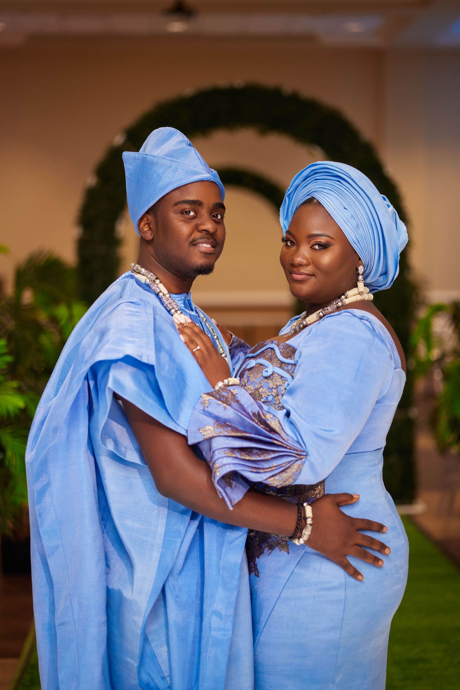Couple in matching blue traditional Nigerian attire posing together at a formal event.