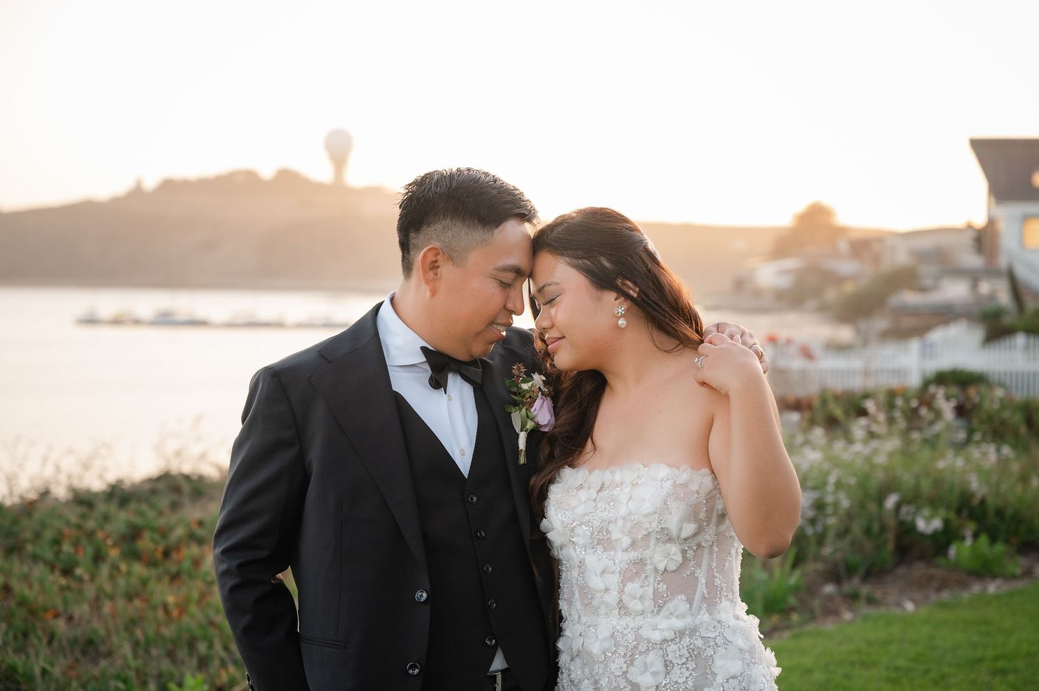 Outdoor wedding ceremony on a cliffside lawn overlooking the Pacific Ocean with guests seated in a semicircle.
