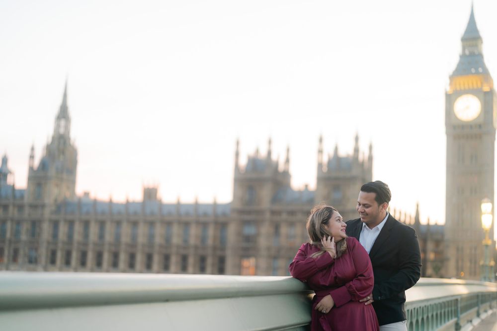 Couple embracing on Westminster Bridge with Big Ben and Houses of Parliament at sunset in London.