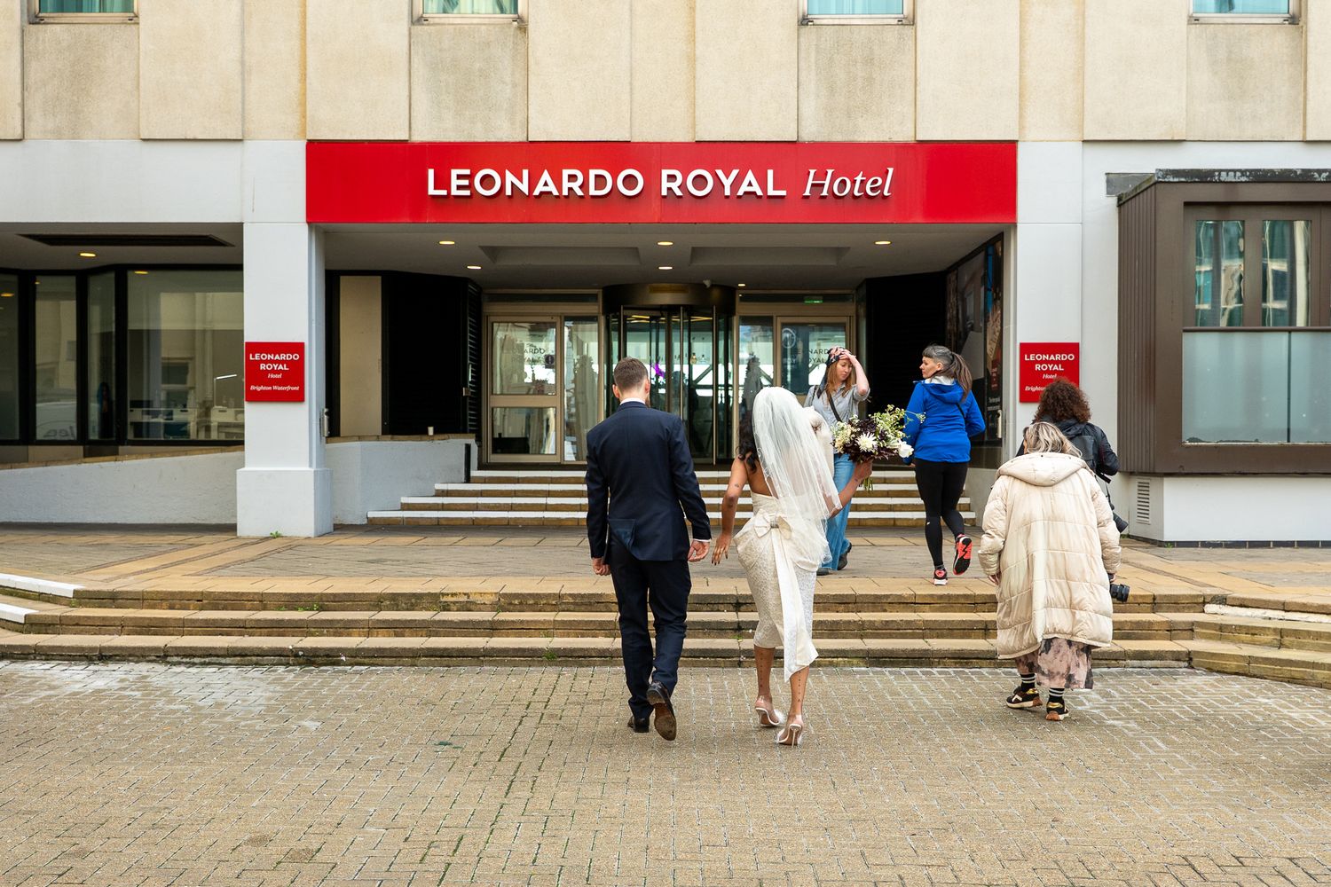 Wedding party arriving at Leonardo Royal Hotel entrance on a bright day.