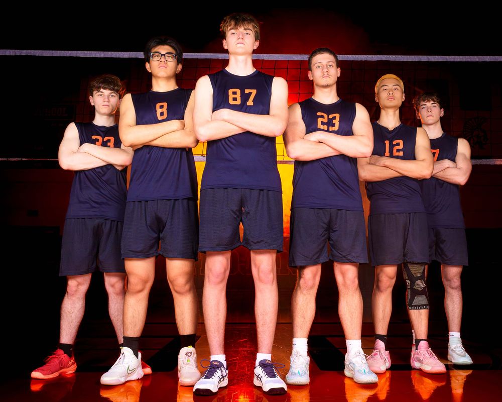 Six Hershey Trojans stand arms crossed at the net against a orange fog backdrop by Deanna Fox, SportsFox Photography based in Hershey PA.
