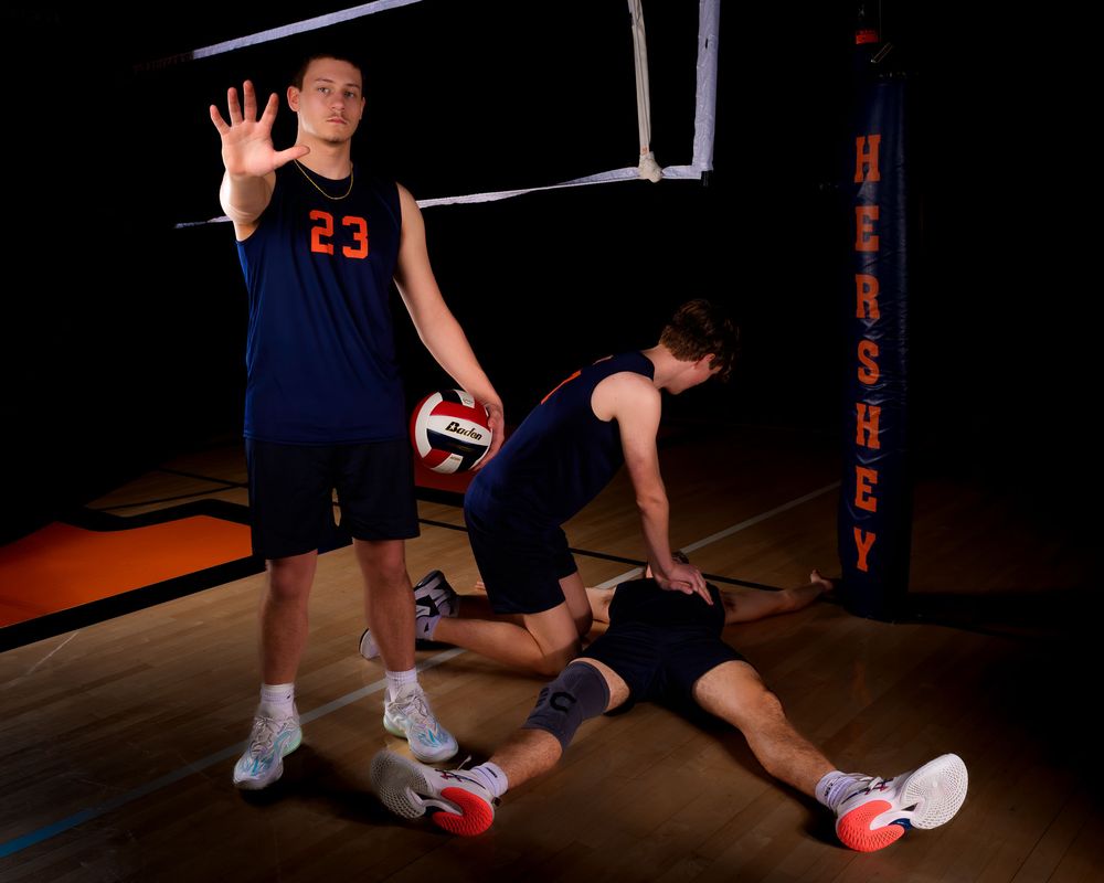 Hershey Trojan #23 raises hand as teammates act out a CPR scene near the net by Deanna Fox, SportsFox Photography based in Hershey PA.