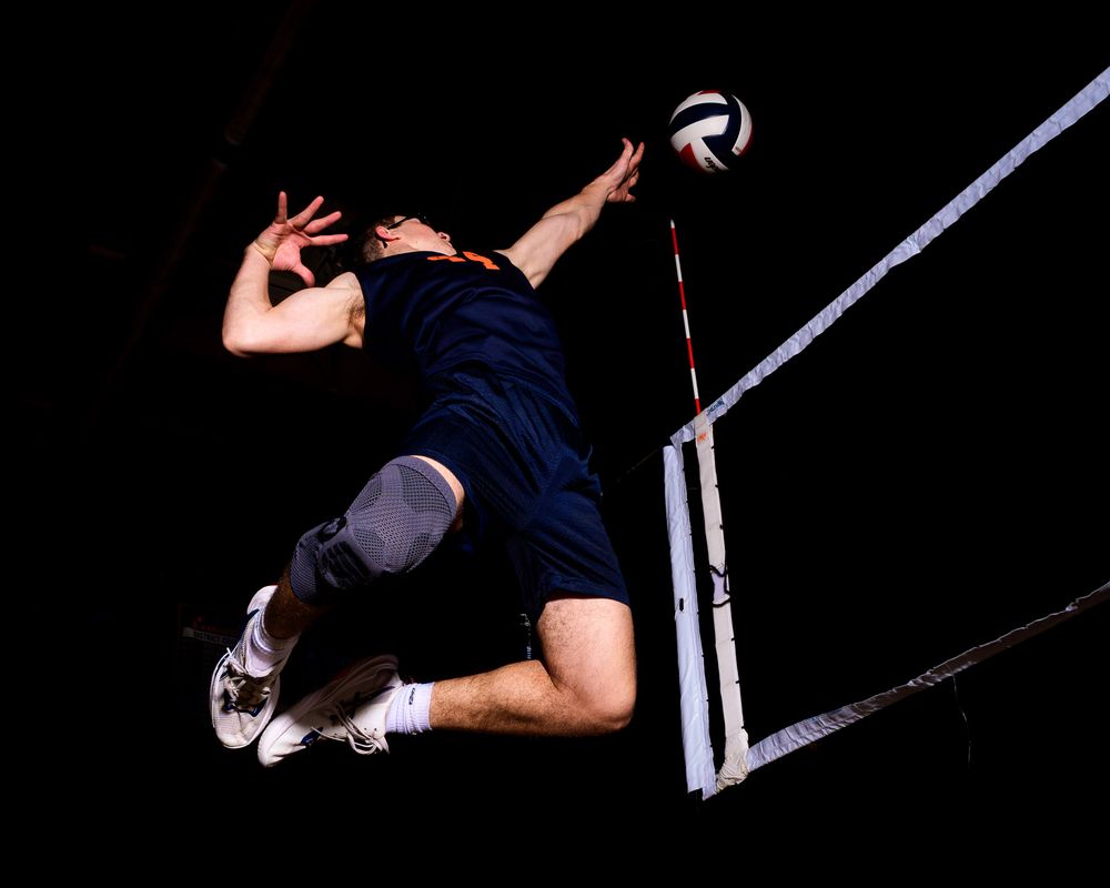 Hershey Trojan spikes volleyball at the net from a dramatic low angle perspective by Deanna Fox, SportsFox Photography based in Hershey PA.