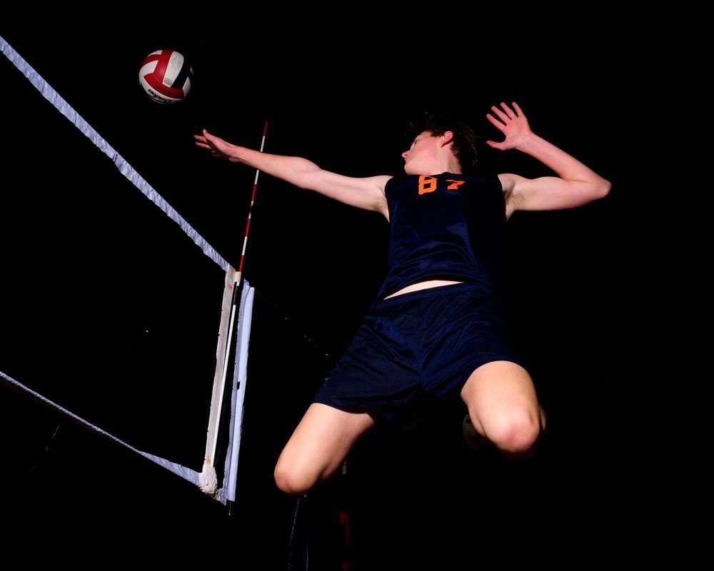 Hershey Trojan #87 leaps to spike the ball over the net, shot from a low angle by Deanna Fox, SportsFox Photography based in Hershey PA.