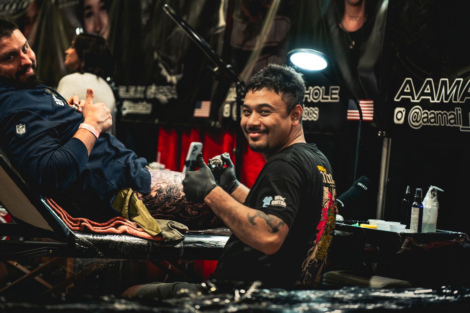Competitive arm wrestling match in progress at a tournament with spectators watching intently in the background.