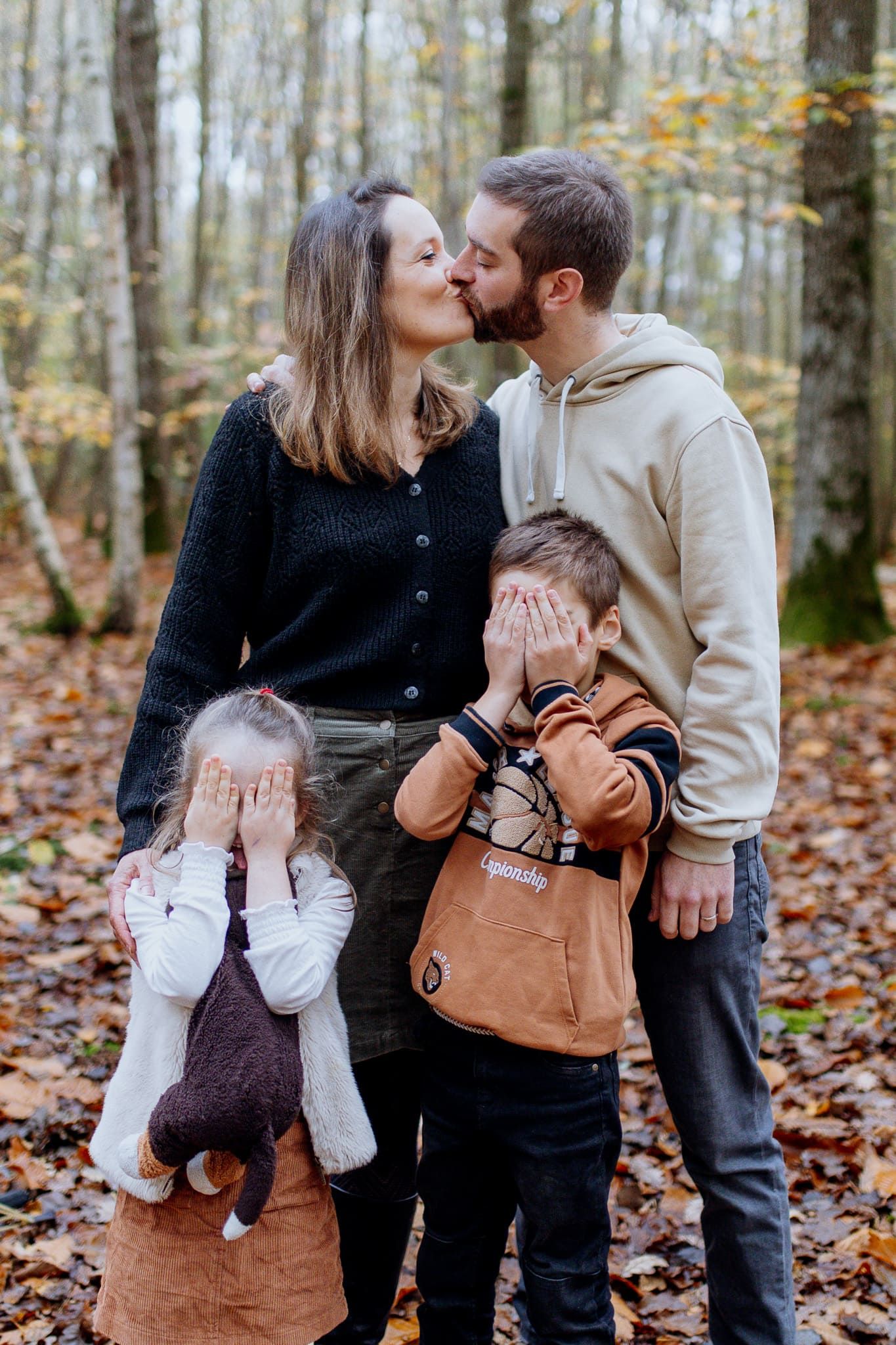 Famille qui joue dans les yvelines, les parents s'embrassent pendant que les enfants se mettent les mains devant les yeux pour ne pas voir
