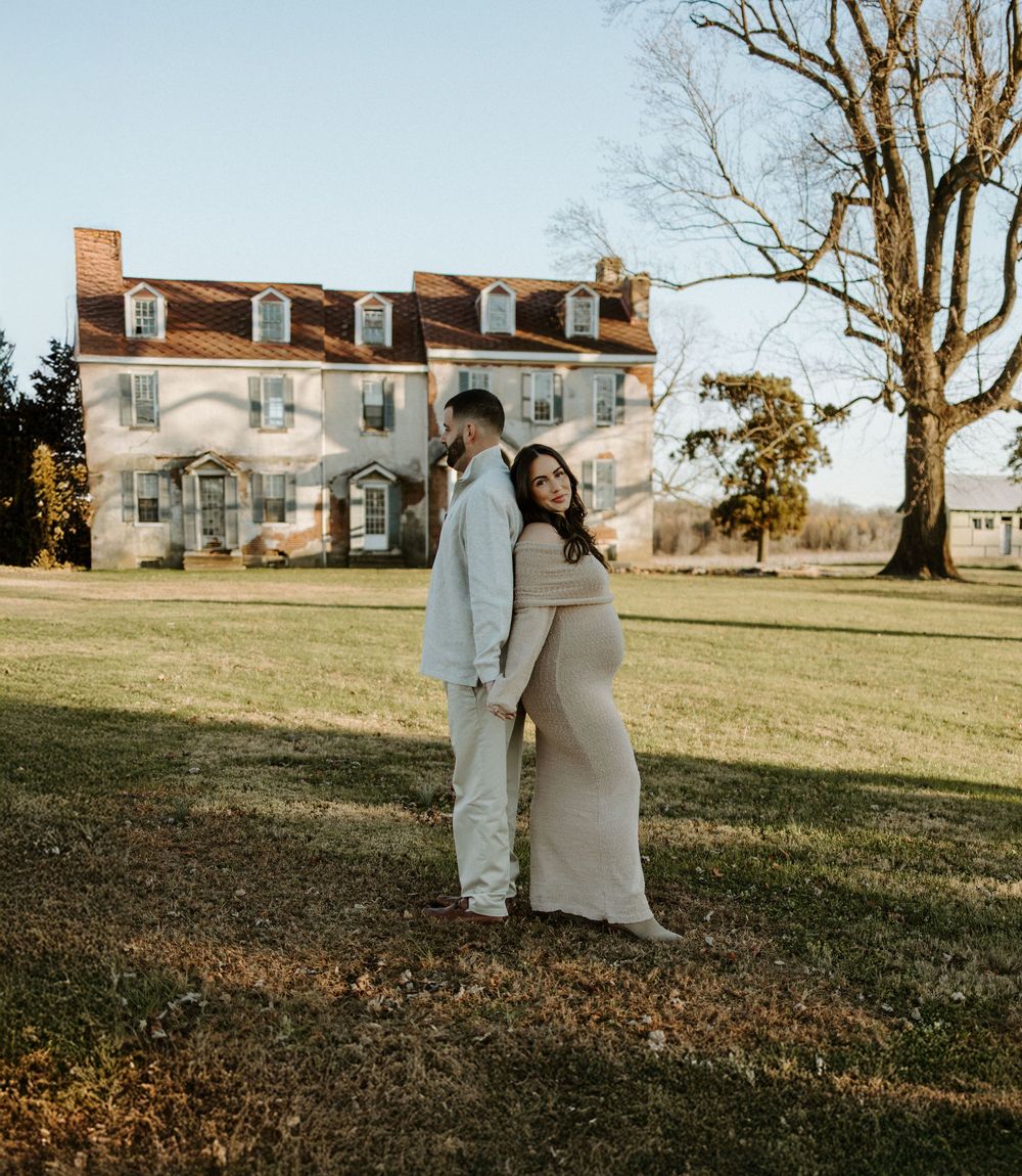 Couple poses in front of historic white house during maternity photoshoot.