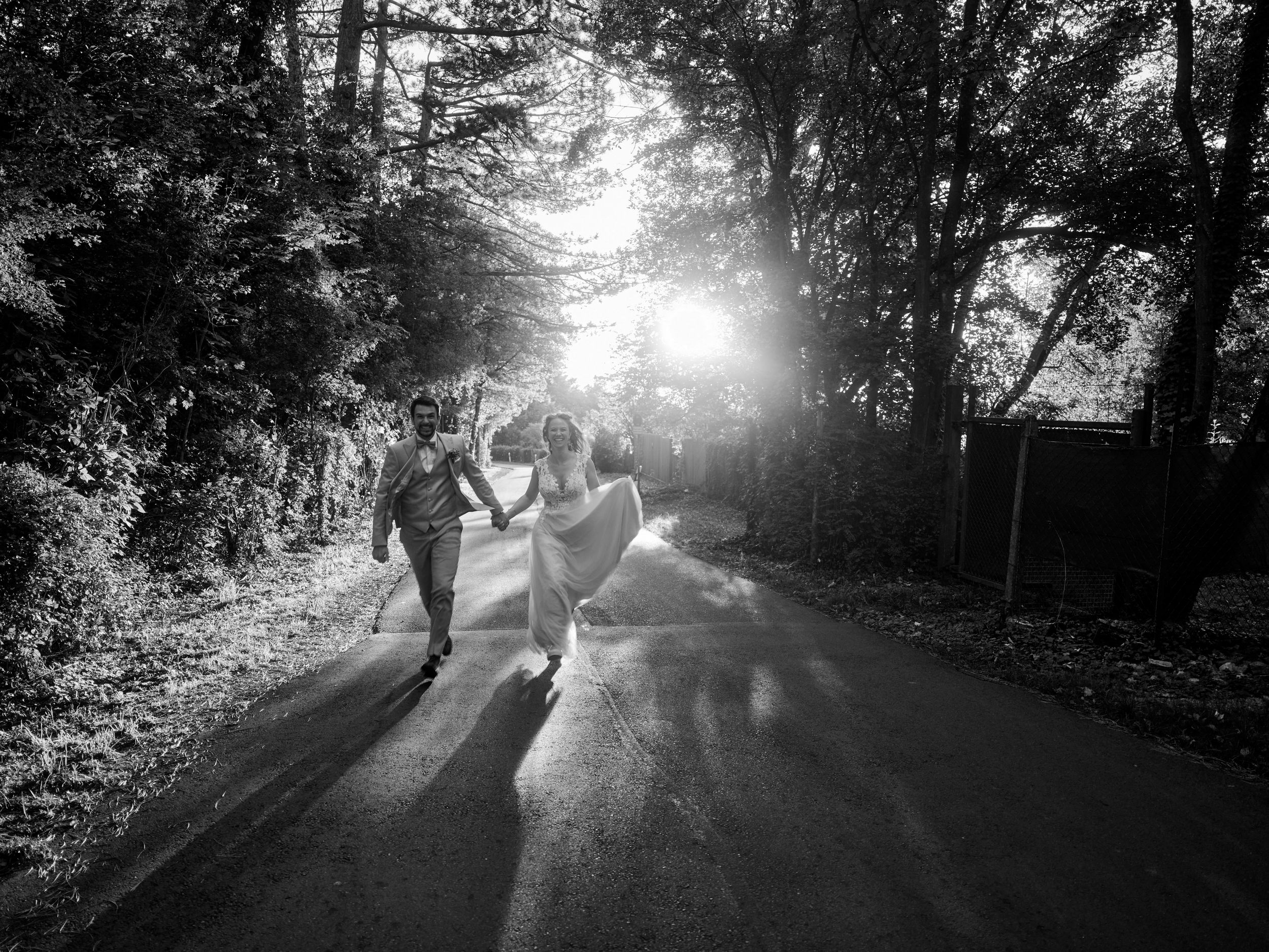A silhouetted couple dances together on a forest path with dramatic sunlight streaming through the trees.
