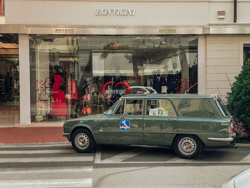 A series of low-angle shots showing the bottom half of parked luxury vehicles against a storefront background.