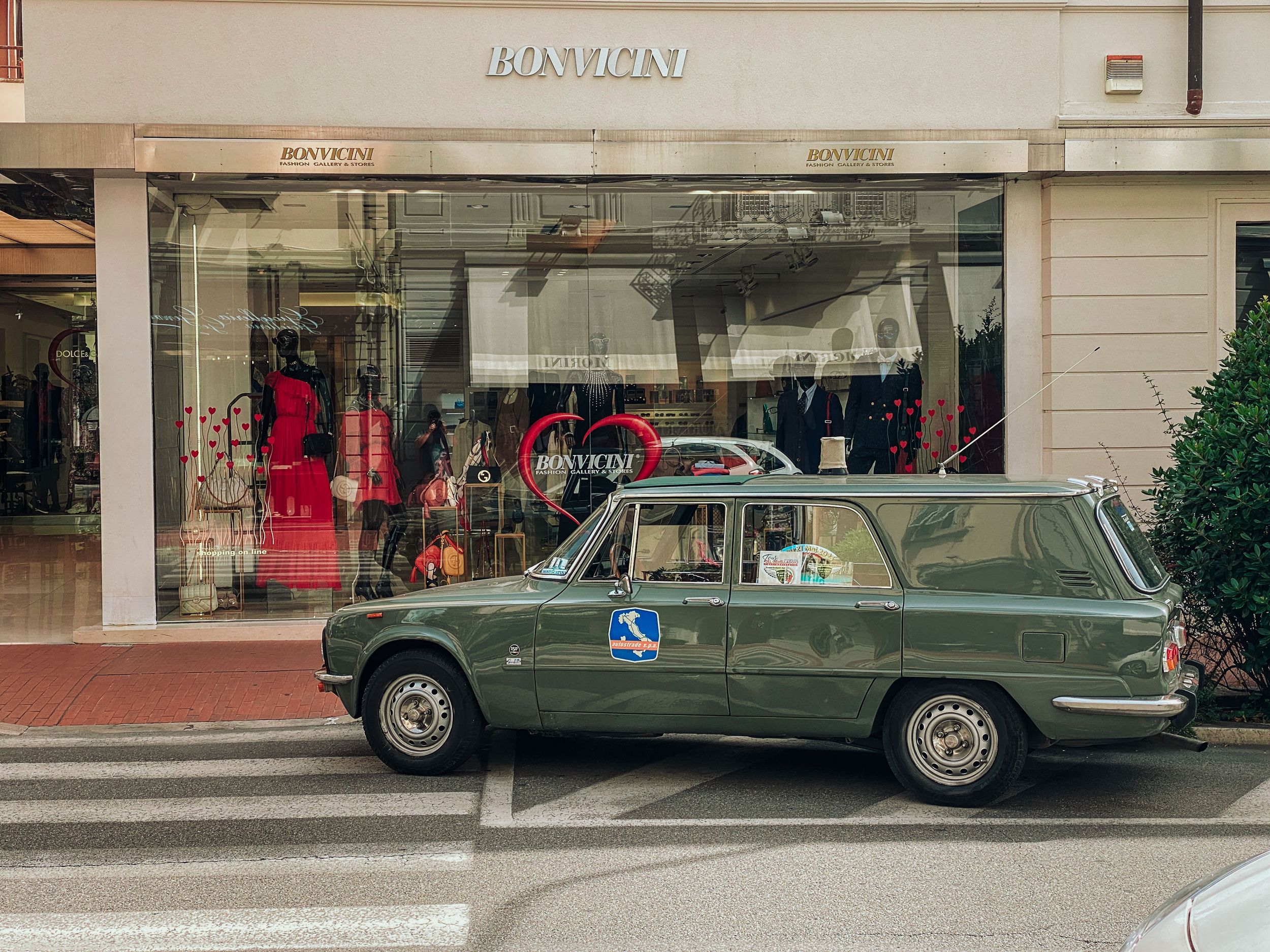 A series of low-angle shots showing the bottom half of parked luxury vehicles against a storefront background.