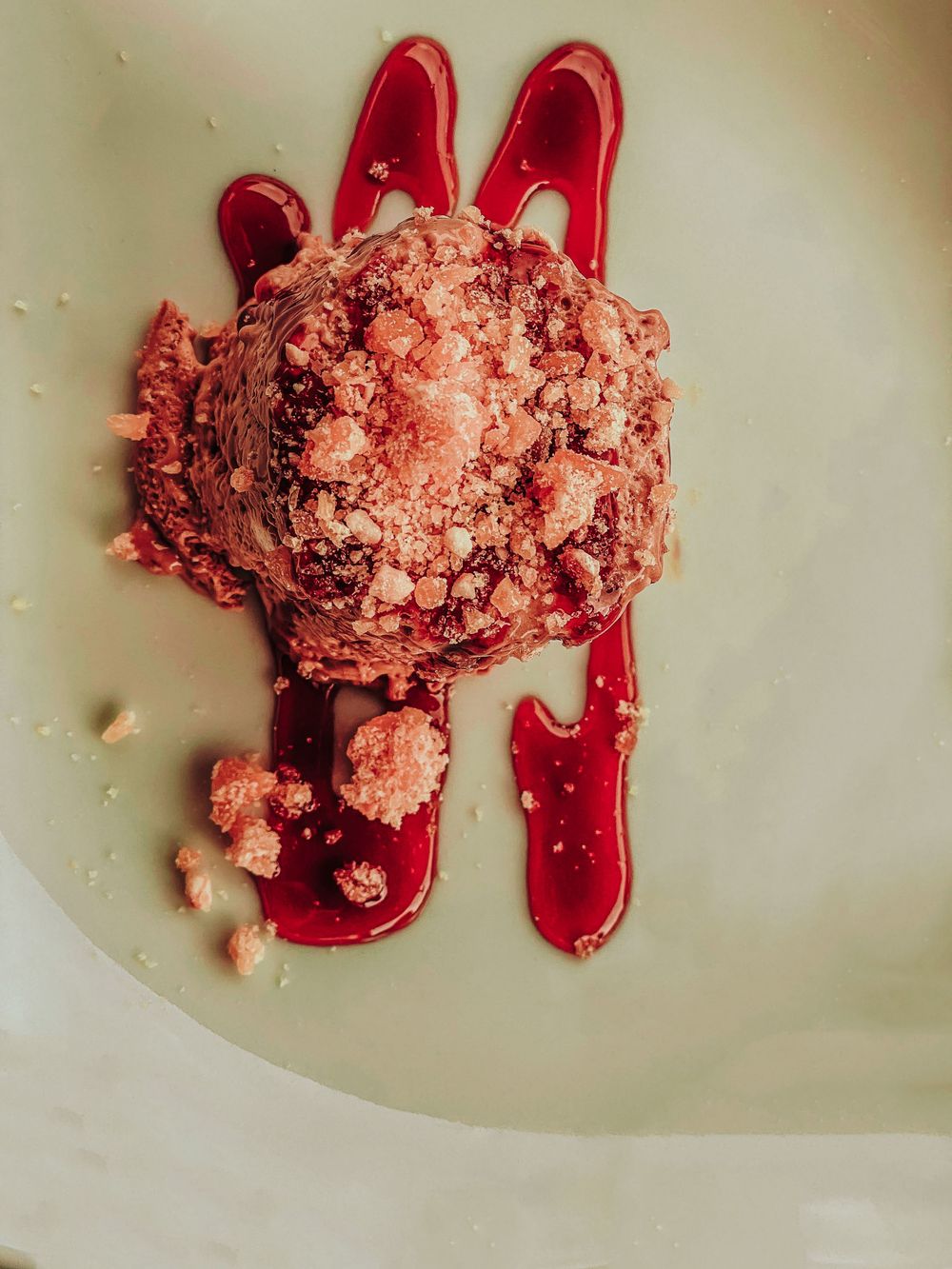Red liquid splashes and crumbs create an artistic pattern on a light colored surface.