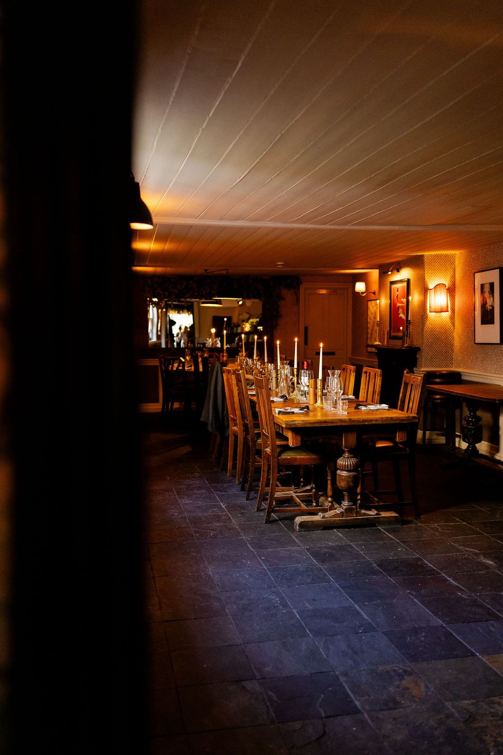 A dimly lit rustic restaurant interior with stone floors and wooden furniture illuminated by warm ambient lighting.