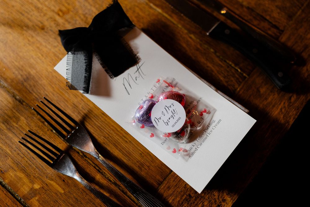 Place settings and menus arranged on dark wooden table at formal event.