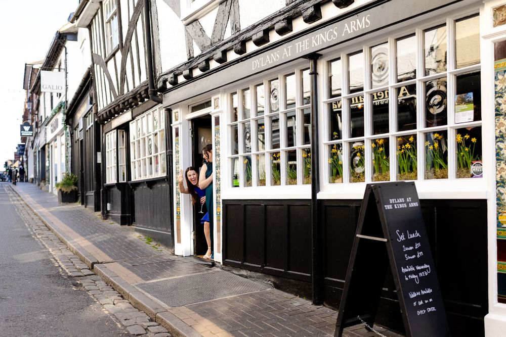 Historic row of white Georgian storefronts with black trim line a charming cobblestone street in London.